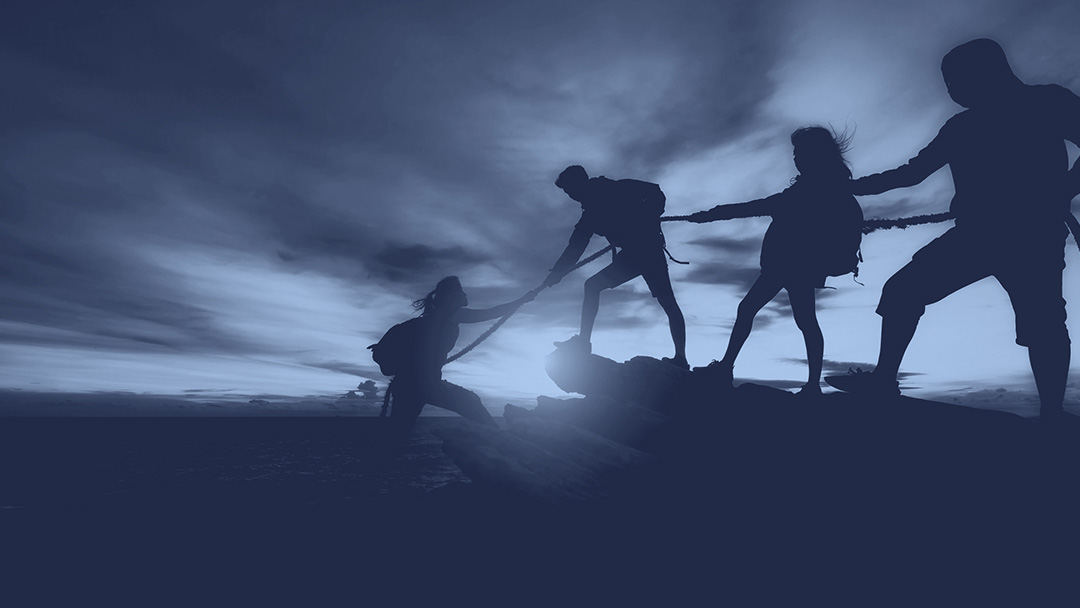 An image of four people rock climbing and working together